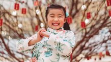 A young girl makes the fist and palm gesture as a Chinese New Years greeting.