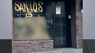Words in gold spray paint cover the front window of Santos' office.