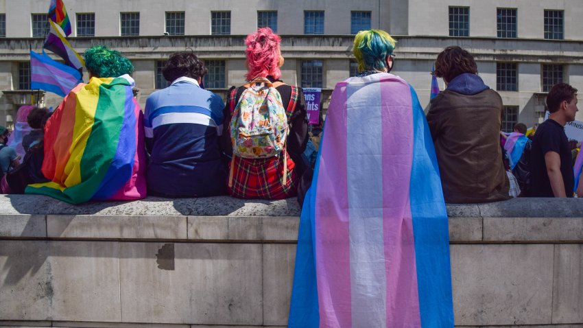 LONDON, UNITED KINGDOM – 2021/08/06: Protesters wrapped in pride and trans pride flags sit on a wall during the trans rights demonstration.
Protesters gathered outside Downing Street demanding an end to discrimination against the trans community, better support from the government against hate, and improvements to trans healthcare waiting times. (Photo by Vuk Valcic/SOPA Images/LightRocket via Getty Images)