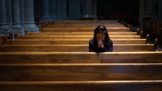 Foto ilustrativa de una persona orando dentro de una iglesia.