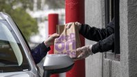 An employee hands an order to a customer through a drive-thru window at a McDonald’s restaurant in Oakland, California, April 9, 2020.