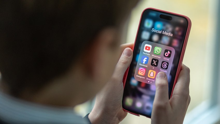 A 12-year-old school boy looks at an iPhone screen showing various social media apps including TikTok, Facebook and X on Feb. 25, 2024.