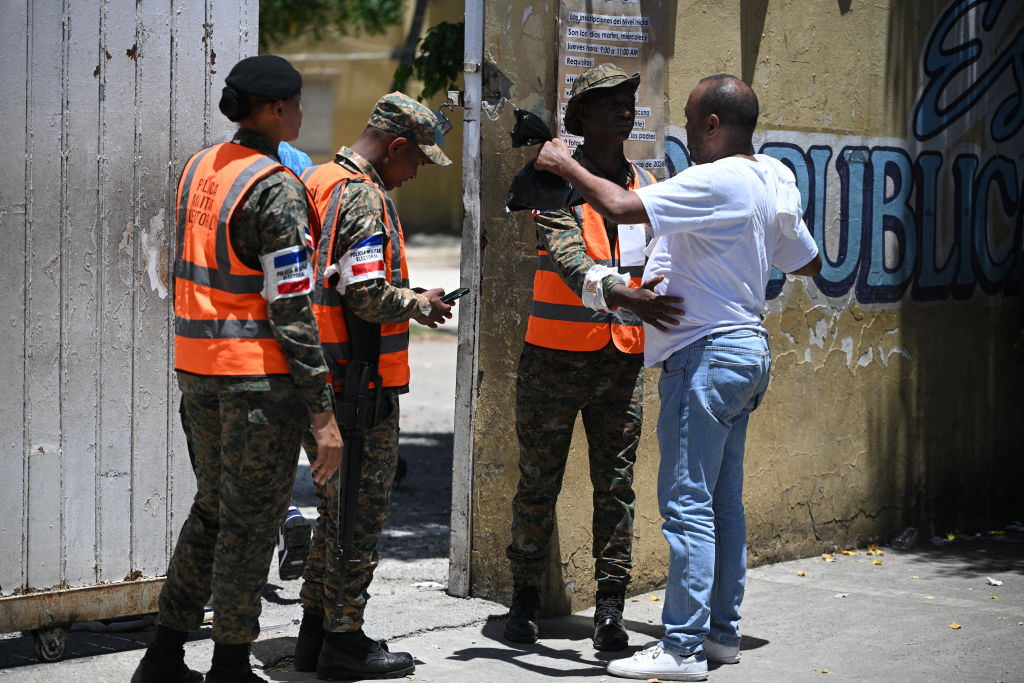 Un miembro de la Policía Electoral Militar cachea a un hombre antes de ingresar a un colegio electoral para votar durante las elecciones generales en Santo Domingo el 19 de mayo de 2024. Las urnas se abrieron el domingo en la República Dominicana, donde el presidente Luis Abinader se prepara para una cómoda reelección el a raíz del apoyo generalizado a su postura dura sobre la migración desde el problemático vecino Haití. (Foto de Federico PARRA/AFP) (Foto de FEDERICO PARRA/AFP vía Getty Images)