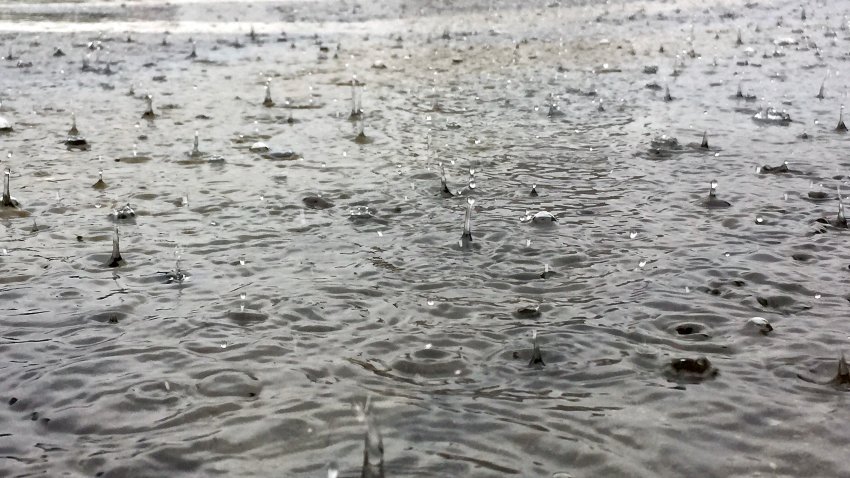 Brooklyn, NYC- October 29, 2017: Close-up view looking surface level at splashing raindrops falling on a large puddle of rushing water in a city street during a torrential rainstorm.