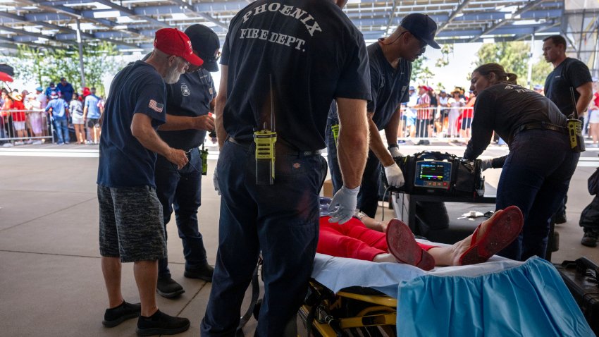 As temperatures reach 108 degrees Farenheit (42C), a woman is tended to for heat exhaustion as supporters line up before former US President and 2024 Republican presidential candidate Donald Trump participates in a town hall event at Dream City Church in Phoenix, Arizona, on June 6, 2024. An extreme early-summer heatwave was expected to peak Thursday across much of the western United States, where millions were scrambling to cope with the sudden sharp rise in temperatures. (Photo by Jim WATSON / AFP) (Photo by JIM WATSON/AFP via Getty Images)