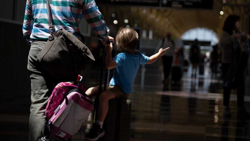 ARLINGTON, VIRGINIA – MAY 24: A boy sits on a rolling suitcase as travelers make their way through Ronald Reagan Washington National Airport on May 24, 2024 in Arlington, VA. AAA projects travelers going 50 miles or more this Memorial Day holiday will be almost 44 million people, a number not seen since 2005. (Photo by Andrew Harnik/Getty Images)