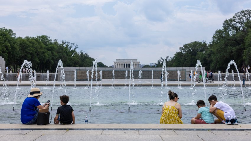 WASHINGTON, DC – JUNE 19: People sit with their feet in the fountain at the World War II Monument amidst a heat wave on the National Mall on June 19, 2024 in Washington, DC. Temperatures in Washington reached 98 degrees as heat rose drastically throughout the East Coast. (Photo by Anna Rose Layden/Getty Images)