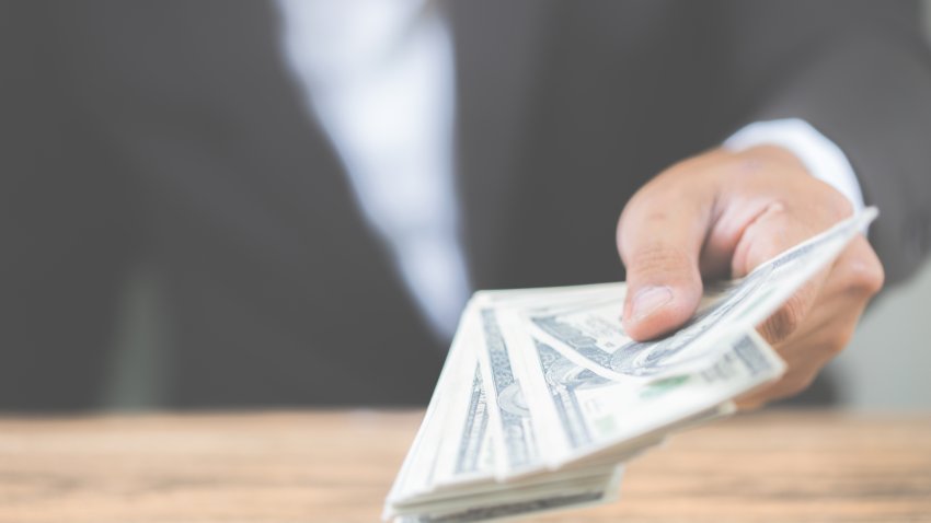 Close up hand of businessman holding money dollar bills on wooden table. Using as concept of corruption , Business corruption, bribe. With copy space for your text.