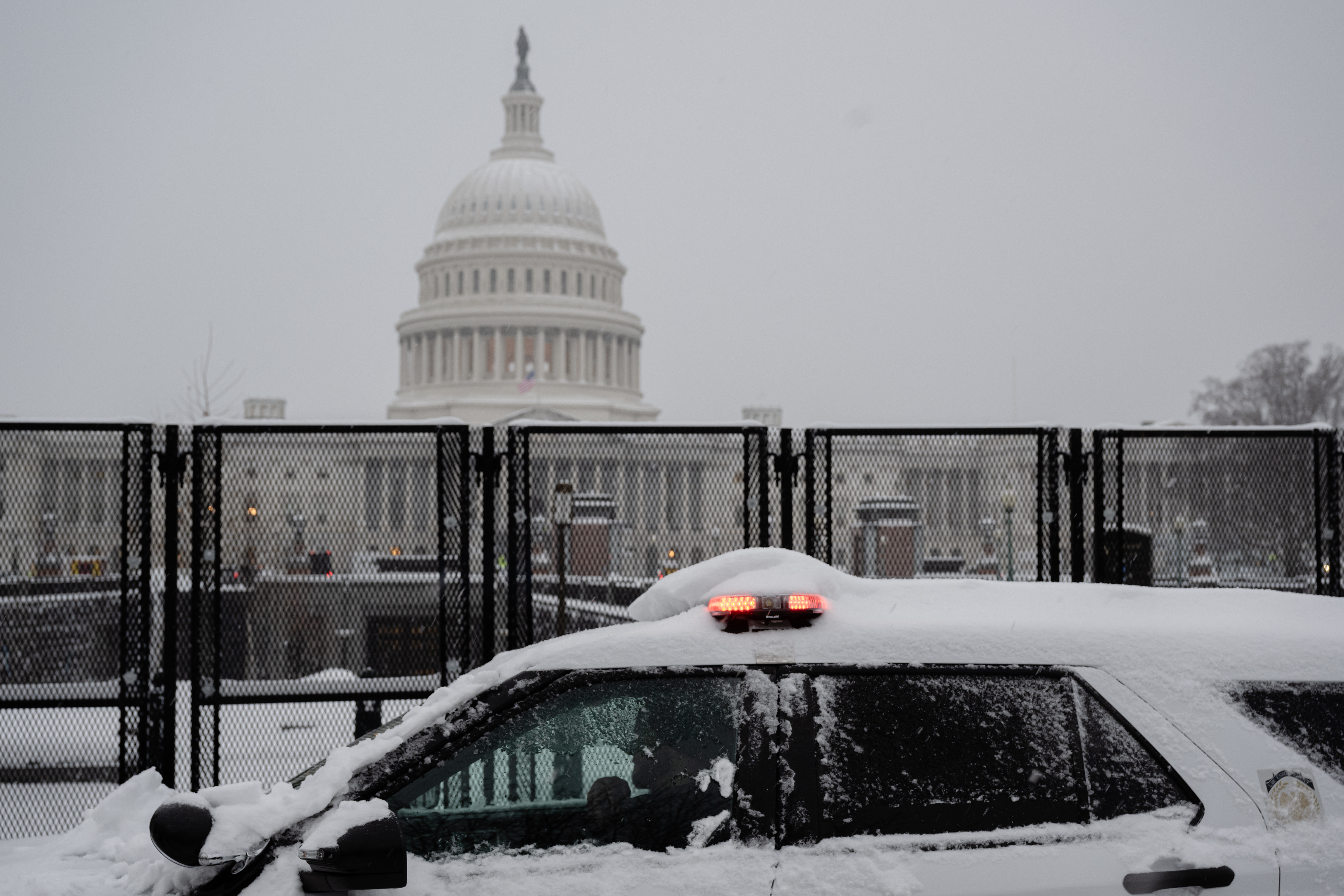 WASHINGTON, DC - 6 DE ENERO: Un vehículo de la policía pasa por la zona vallada de seguridad que rodea el Capitolio de EEUU durante una tormenta de nieve el 6 de enero de 2025 en Washington, DC. Se están llevando a cabo preparativos de seguridad reforzados para la certificación del voto electoral del próximo 6 de enero, el funeral de Estado del presidente Carter y la inauguración. (Foto de Jon Cherry/Getty Images)