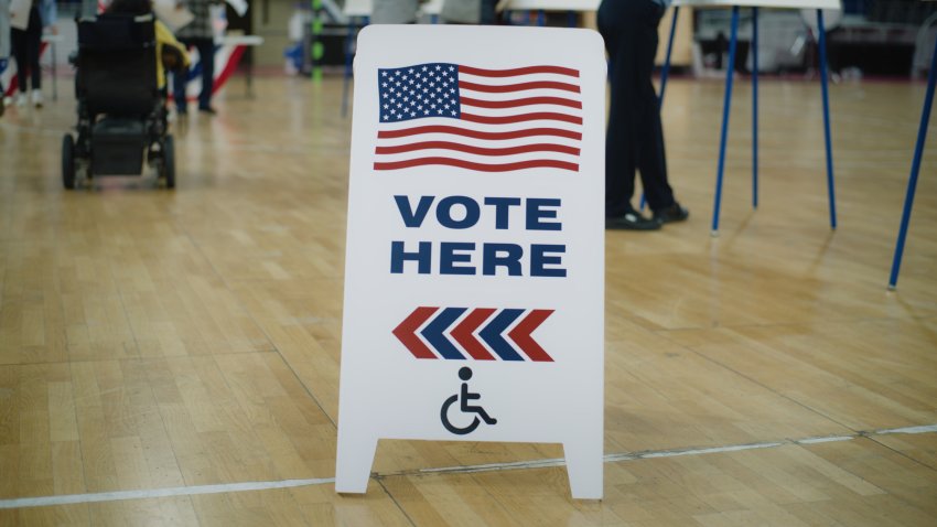 Vote here sign on floor. Woman with spinal muscular atrophy in electric wheelchair comes to vote in polling station. Political races of US presidential candidates. National Election Day. Dolly shot.