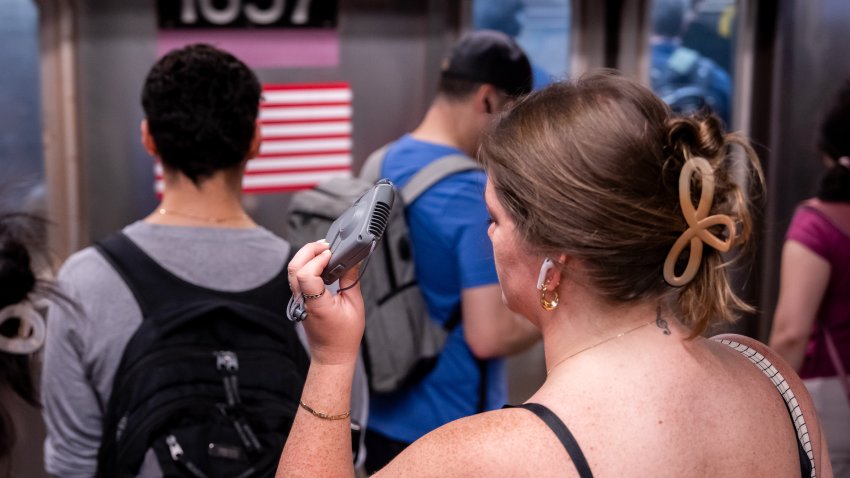A commuter uses a hand fan at the 14th Street-Union Square subway station during high temperatures in New York, US, on Monday, June 23, 2025. In addition to posing health risks, the blistering weather will boost electricity demand and strain aging transportation infrastructure, including subways and commuter rail. Photographer: Adam Gray/Bloomberg via Getty Images