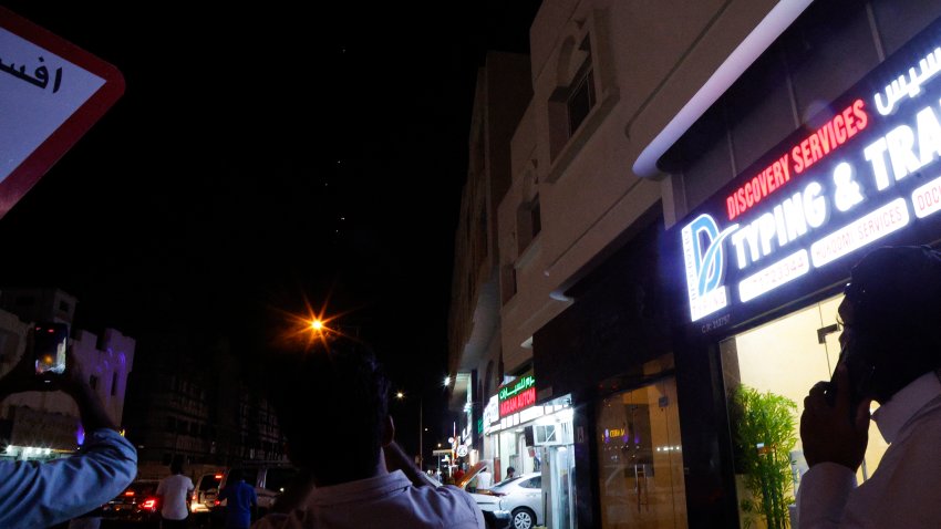 TOPSHOT – People film projectiles over a street lamp in Doha, Qatar, on June 23, 2025. Qatar on June 23, 2025 condemned an Iranian attack on the largest US military base in the region, hosted in the Gulf state, calling it a  “flagrant violation” of its sovereignty”. (Photo by AFP) (Photo by -/AFP via Getty Images)