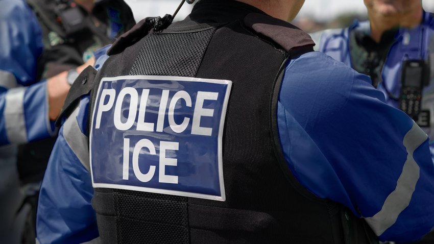 ICE police agent – Officer of Immigration and Customs Enforcement. Close-up of POLICE ICE marking on the back of a stab proof vest uniform worn by a trio of police officers at the scene of an incident