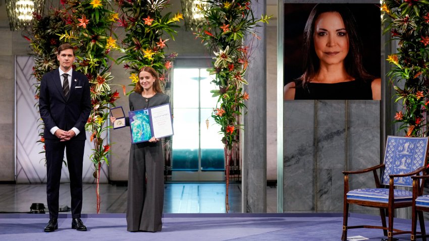 TOPSHOT &#8211; Ana Corina Sosa (R), daughter of Venezuelan opposition leader Maria Corina Machado, receives the Nobel Peace Prize for her mother from the Chair of the Norwegian Nobel Committee Jorgen Watne Frydnes next to a photo Maria Corina Machado who could not attend the Nobel Peace Prize ceremony at Oslo City Hall on December 10, 2025 in Oslo, Norway. The 2025 Nobel Peace Prize was awarded to Machado for her efforts to bring democracy to Venezuela, challenging the iron-fisted rule of Venezuelan President Nicolas Maduro, who has been president since 2013. (Photo by Ole Berg-Rusten / NTB / AFP via Getty Images) / Norway OUT
