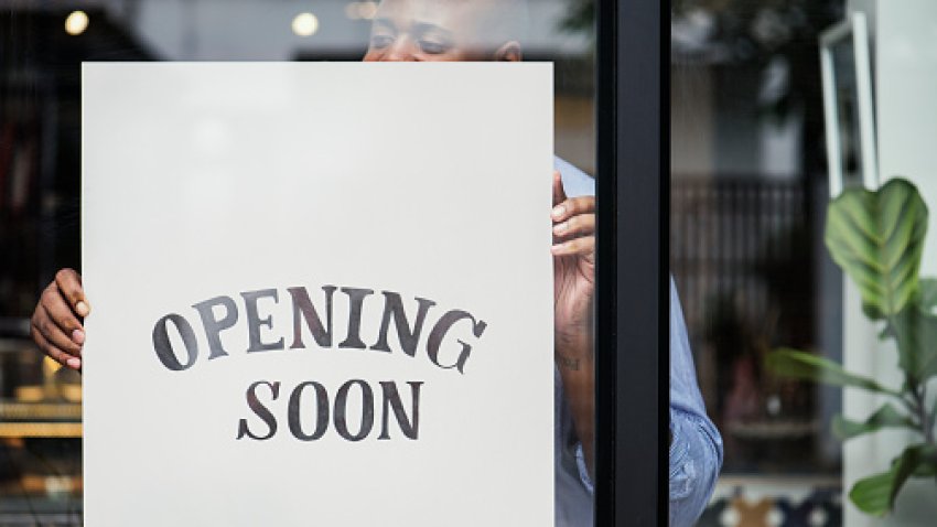 Man putting on store opening soon sign