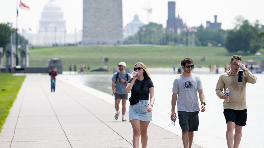 Tourists drink water as they walk along the National Mall near the Washington Monument in Washington, DC, July 25, 2025, as a heat dome sits over the region leading to extremely high temperatures. (Photo by SAUL LOEB / AFP) (Photo by SAUL LOEB/AFP via Getty Images)
