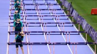 Volunteers prepare hurdles before the women's 100m hurdles during the Paris 2024 Olympic Games.